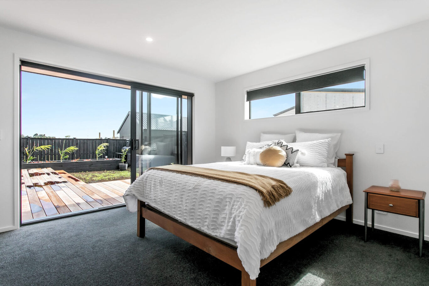 staged bedroom with sliding door to deck of new build home at paerata rise