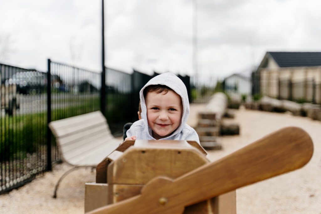A happy boy playing on a wooden plane at Paerata Rise's park