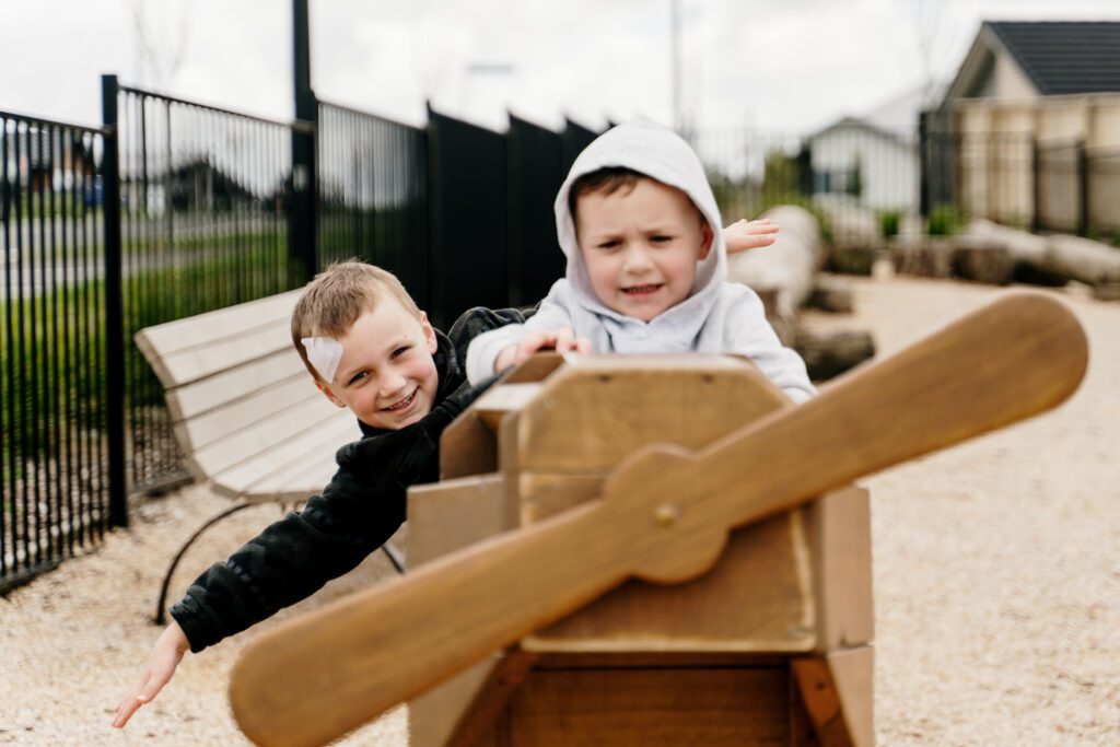 2 boys playing on a wooden plane at a park in Paerata Rise